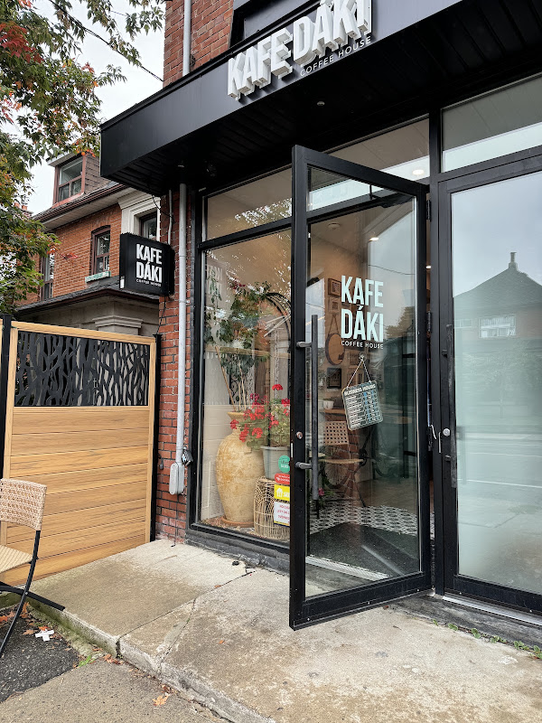 Open glass entrance door with the Kafe Dáki wordmark